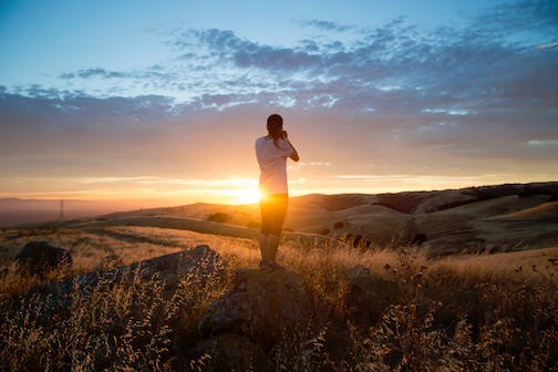 Woman on a farm looking at the sunset. 